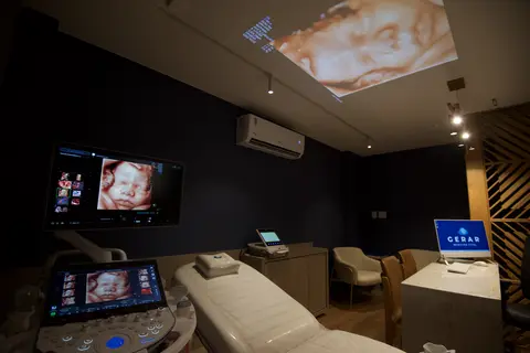 Sala de exame com o Voluson, a maca e o logo da Gerar no monitor
