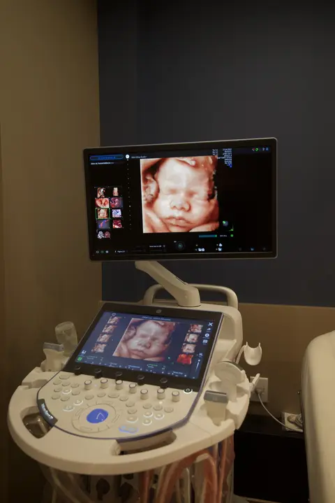 Sala de exame com maca e monitor na parede